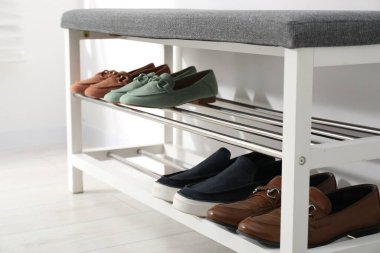 Beyaz duvarın yanında farklı ayakkabıları olan ayakkabı deposu tezgahı, yakın plan.