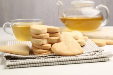 Lezzetli kalp şeklinde kurabiyeler ve çay beyaz masada, yakın plan.