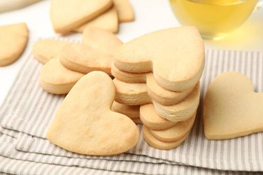 Lezzetli kalp şeklinde kurabiyeler ve çay beyaz masada, yakın plan.