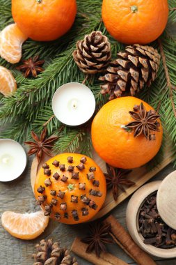 Olgun mandalinalar, baharatlar, koniler, köknar ağacı dalları ve ahşap masada yanan mumlar, düz uzanmış.