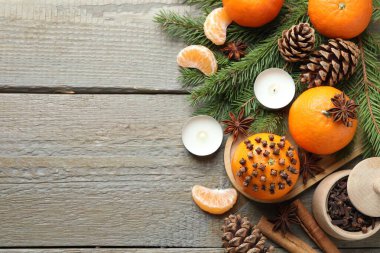 Olgun mandalinalar, baharatlar, koniler, köknar ağacı dalları ve ahşap masada yanan mumlar. Metin için boşluk