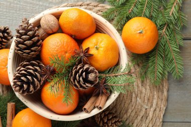 Olgun mandalinalar, baharatlar, koniler, cevizler ve ağaç dalları ahşap masa, üst görünüm