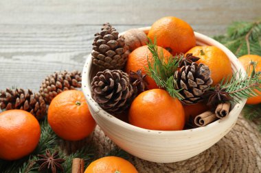 Olgun mandalinalar, baharatlar, koniler, ceviz ve köknar ağacı dalları ahşap masada, yakın plan