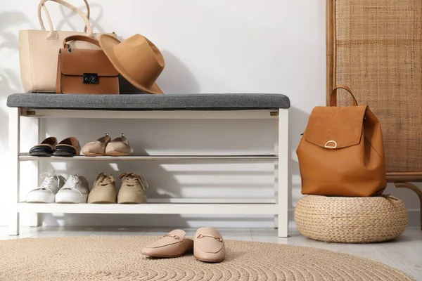 Beyaz duvarın yanında farklı ayakkabı ve aksesuarlarla dolu bir ayakkabı deposu.