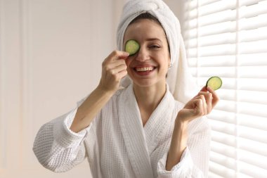 Havluya sarılı güzel bir kadın ve pencerenin yanında salatalık dilimleri.