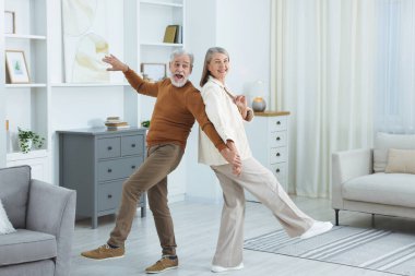 Mutlu yaşlı çift evde dans ediyor.