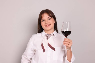 Açık gri arka planda kırmızı şarap kadehi olan profesyonel şarap garsonu.