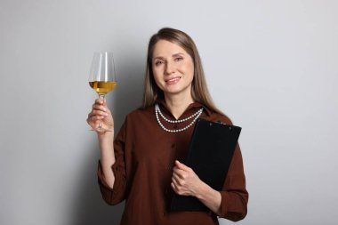 Açık gri arka planda beyaz şarap ve panosu olan profesyonel şarap garsonu.