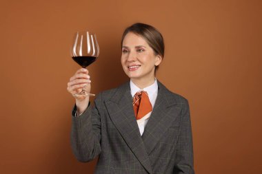 Kahverengi arka planda kırmızı şarap kadehi olan profesyonel şarap garsonu.