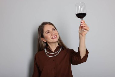 Açık gri arka planda kırmızı şarap kadehi olan profesyonel şarap garsonu.