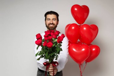 Sevgililer Günü. Buketi ve kalp şeklinde balonları olan bir adam.