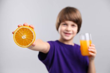 Açık gri arka planda taze portakal suyu ve meyveli çocuk, seçici odaklı.