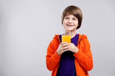 Açık gri arka planda bir bardak taze portakal suyu olan çocuk. Metin için boşluk