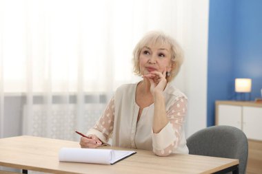 Ahşap masada son dilek ve vasiyetnameyi imzalayan üst düzey bir kadın.