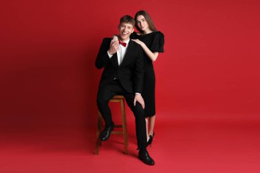 Kırmızı arka planda şık giyinen mutlu çift.