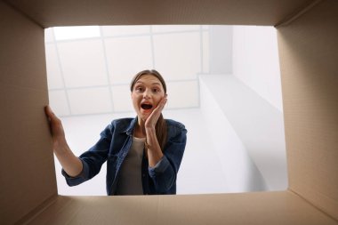 Kadın içerideki karton kutuya bakıyor, içerideki paketi görüyor.