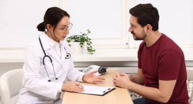 Klinikteki ahşap masada pano danışmanı olan bir doktor.