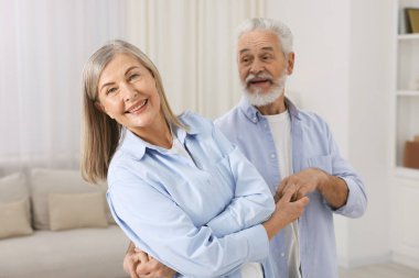 Mutlu yaşlı çift evde dans ediyor.