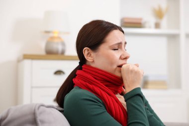 Evdeki kanepede öksüren bir kadın. Soğuk Semptom