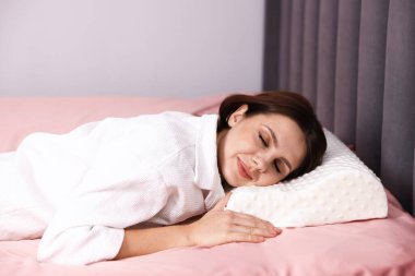 Evde ortopedik yastıkla uyuyan genç bir kadın. Sağlıklı duruş