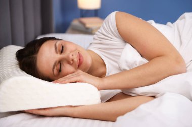 Evde ortopedik yastıkla uyuyan genç bir kadın. Sağlıklı duruş