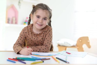 Masada kalemle resim çizen sevimli küçük kız. Metin için boşluk