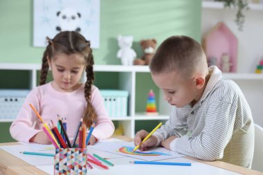 Çocuklar kalemle çizim yapıyorlar.