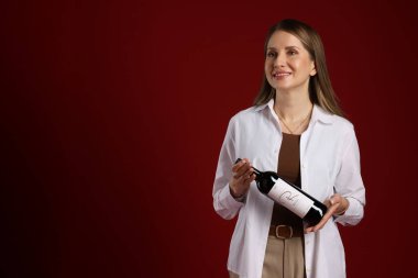 Kırmızı arka planda şarap şişesi olan profesyonel şarap garsonu. Metin için boşluk