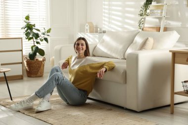 Evdeki koltuğun yanında dinlenen bir kadın.