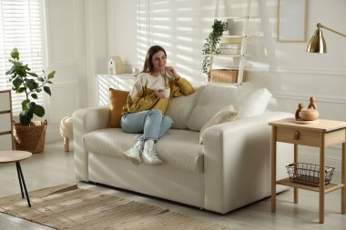 Evdeki kanepede dinlenen mutlu bir kadın.