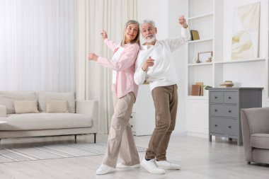 Mutlu yaşlı çift evde dans ediyor.