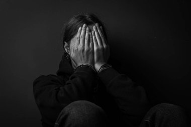 Yüzünü saklayan kelepçeli kadın. Yakalanan suçlu. Siyah ve beyaz tonlama