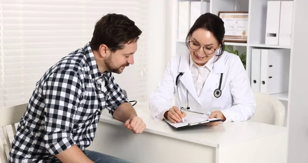 Klinikteki beyaz masada pano danışmanı olan bir doktor.