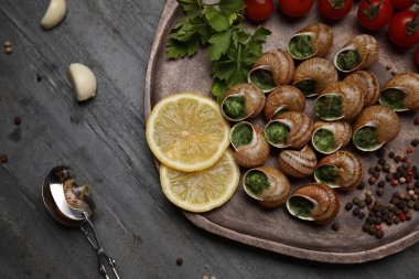 Gri masada servis edilen lezzetli pişmiş salyangozlar.