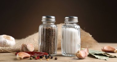 Ahşap masa üzerinde baharatlı tuzluk ve biber karıştırıcılar kahverengi eğimli arka plan, yakın çekim