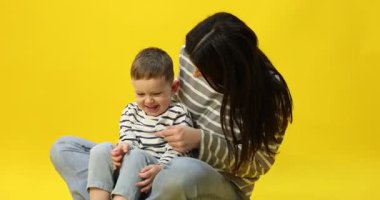 Mutlu anne sarı arka planda oğluna sarılıyor.