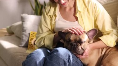 Evdeki kanepede sevimli köpeğini okşayan bir kadın.