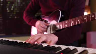 Stüdyoda elektro gitar ve sentezleyici çalan adam, yakın plan.