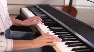 Evde sentezleyici oynayan kadın, yakın çekim görünümü