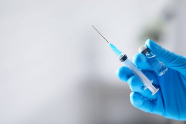 Hafif arka planda aşı ve şırınga şişesi olan hemşire, yakın plan. Metin için boşluk