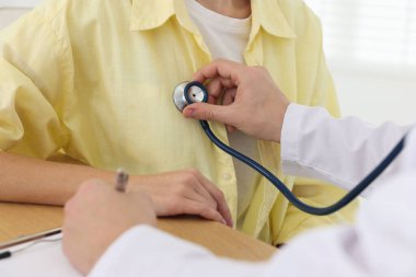 Doktor hastanede steteskopla kadının kalp atışlarını kontrol ediyor.