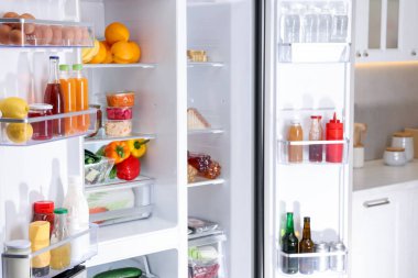 Mutfakta farklı taze gıda ürünleri olan modern buzdolabı.