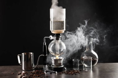 Gri masadaki vakumlu kahve makinesinde aromatik kahve demlemek, yakın plan.