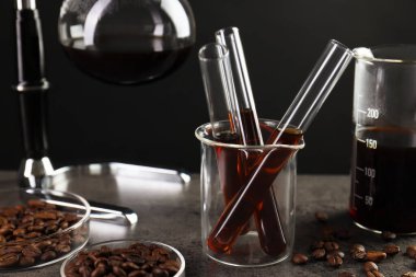 Kahve, fasulye ve labaratuar camlı elektrikli süpürge gri masada, yakın plan.