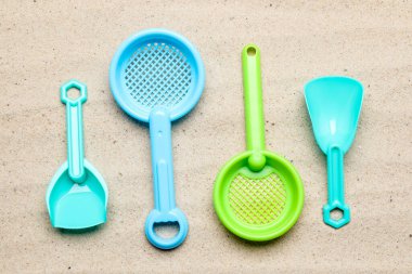 Plastic shovels and sifters on sand, flat lay. Children's beach toys