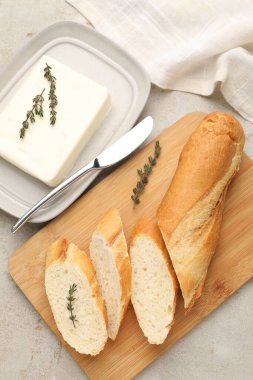 Gri desenli masada tereyağlı baget, kekik ve bıçakla kes, düz uzan.