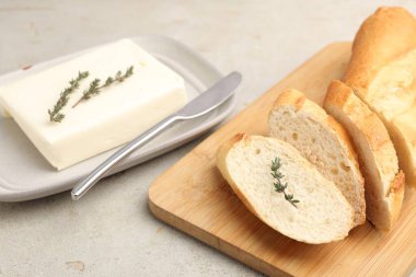 Gri desenli masada tereyağlı baget, kekik ve bıçak, yakın plan.