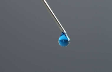 Tüp bebek tedavisinde. Gri arka planda sıvı numunesi olan iğne, yakın plan. Metin için boşluk