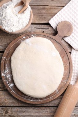 Hamur, merdane ve un ahşap masada, düz yatıyordu.