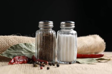 Siyah arka plana karşı baharatlı tuzluk ve biber karıştırıcılar, yakın plan.